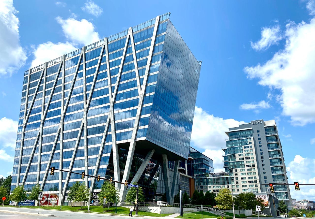Tall modern office building with glass facade in an urban setting under a clear blue sky.